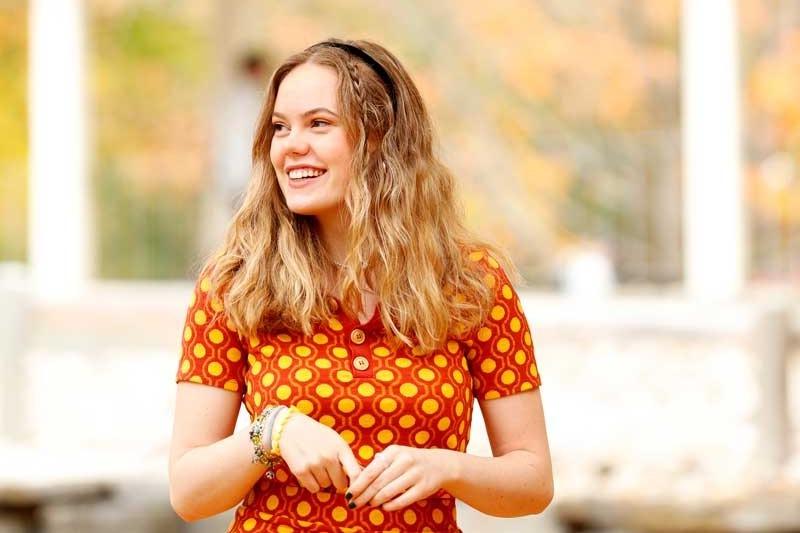 A young woman with blonde hair walks outside on a fall day 